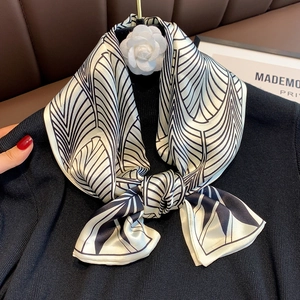 Detail of silk scarf with black geometric pattern and white camellia flower brooch