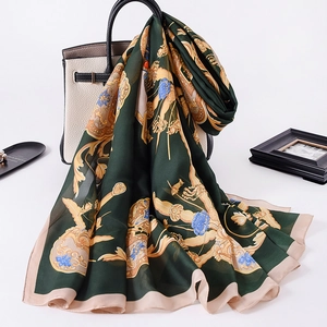 Luxurious dark green scarf with golden baroque floral patterns draped over a stylish handbag