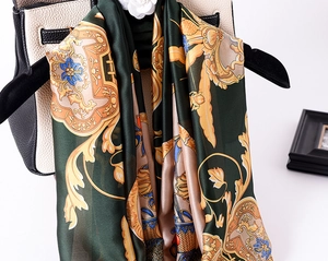 Detailed macro view of baroque floral pattern on glossy dark green satin silk scarf