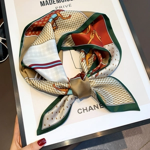 Detail of silk scarf with equestrian patterns and emerald green edges on a frame