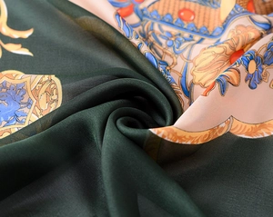 Detailed close-up of dark green silk scarf with golden Baroque floral patterns