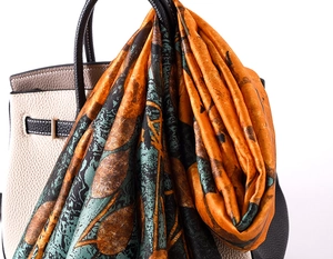 Close-up of artistic silk scarf with vintage abstract print tied on a handbag handle