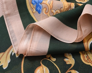 Detail of soft green silk scarf featuring baroque golden patterns and floral prints