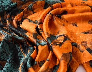 Macro shot of abstract orange and teal print scarf with silk texture and elegant drape