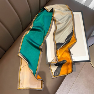 Detailed view of the silk scarf featuring abstract prints and contrast color edges