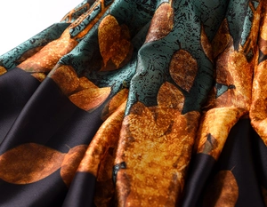 Macro shot of silk texture with vintage orange leaf patterns on black satin fabric
