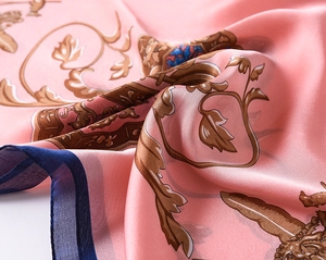 Close-up of pink silk scarf featuring elegant baroque patterns and silky texture details