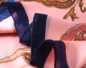 Detailed macro view of soft pink silk scarf with floral patterns and satin texture