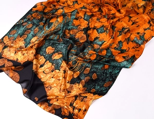 Detailed view of autumn leaf print silk scarf with artistic orange and brown patterns