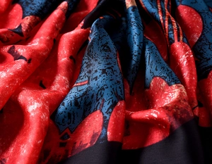 Macro detail of vintage floral silk scarf fabric with rich red and blue abstract patterns