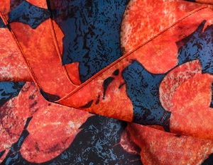 Macro detail of abstract orange and blue print fabric with fine rolled hem finishing