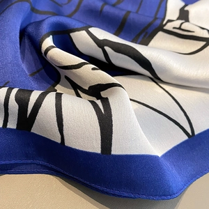 Detailed macro view of the smooth silk fabric texture and rolled hem of the scarf