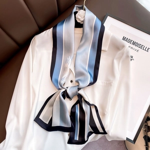 Elegant blue striped silk scarf styled with a white shirt and camellia brooch