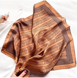 Macro view of silk scarf with black chevron pattern on deep caramel satin fabric