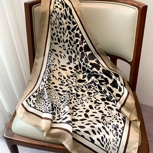 Detail of elegant leopard print silk scarf with glossy texture draped on a wooden chair