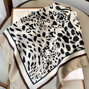 Detail view of leopard print silk scarf with geometric border on a white shirt