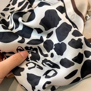 Close-up of leopard pattern silk scarf showing soft texture and glossy finish