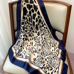 Detailed view of leopard print silk scarf draped on a chair showing silky texture