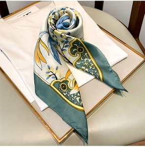 Detailed view of floral silk scarf with baroque patterns on white shirt and golden tray