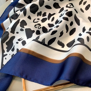 Detailed view of leopard print silk scarf with satin luster and navy blue border trim