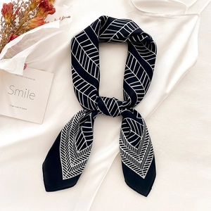 Elegant black silk scarf with white geometric leaf patterns tied in a chic bow knot