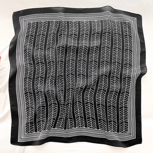 Detail of silk-like scarf featuring black and white chevron patterns and geometric border