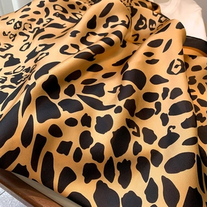 Detail shot of leopard print silk scarf showing satin texture and orange fabric folds