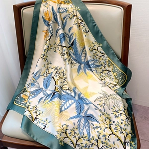 Close-up of floral silk scarf with blue leaf patterns draped on a wooden chair