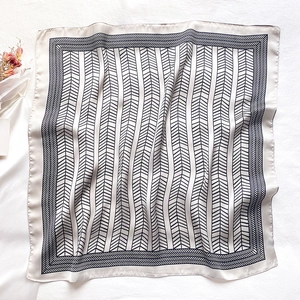 Macro shot of faux silk scarf featuring black herringbone patterns and geometric borders