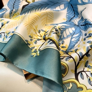 Close-up of artistic floral silk scarf showing premium satin texture and leaf pattern