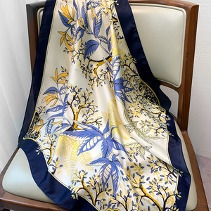 Close-up of floral silk scarf with cream and navy patterns draped on a wooden chair