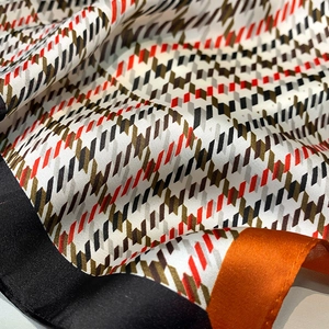 Détail de la texture satinée et du motif pied-de-poule sur l'écharpe en soie
