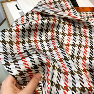 Détail d'un foulard en satin soyeux avec motif pied-de-poule classique et drapé doux