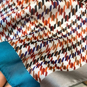 Détail macro d'un foulard en soie à motif pied-de-poule orange et violet élégant