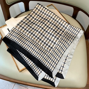 Détail d'un foulard en soie à motif pied-de-poule noir blanc et or sur une chaise