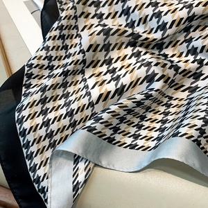 Détail d'un foulard en soie à motif pied-de-poule et bordure noire sur cuir