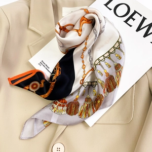 Détail d'un foulard en soie avec motif chaîne sur un blazer beige pour un style élégant