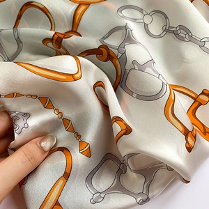 Détail d'un foulard en soie avec motif de chaîne équestre et texture satinée lisse