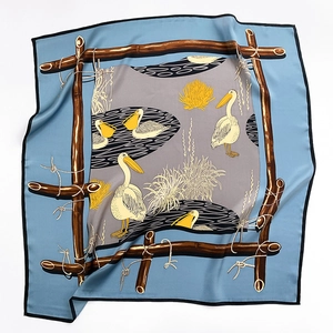 Détail d'un foulard carré en soie avec motif pélican et bordure bleue aux coutures fines