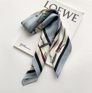 Détail d'un foulard en soie avec motifs équestres et bordures rayées sur un livre