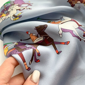 Gros plan du foulard en soie bleu clair montrant l'imprimé polo et le satin