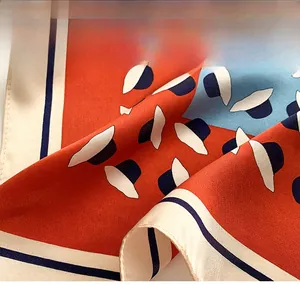 Détail du foulard en soie montrant la couture précise des bords et le motif élégant