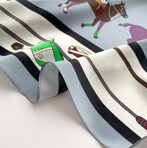 Macro de l'imprimé équestre et des plis soyeux sur le foulard en soie élégant
