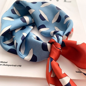 Détail d'un foulard en soie rouge et bleu avec motif chapeau sur un magazine de mode