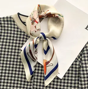 Détail macro du foulard en soie avec imprimé équestre sur un pull en maille pied-de-poule