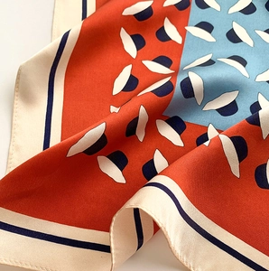 Gros plan d'un foulard en soie montrant des blocs orange et bleu avec imprimé chapeau