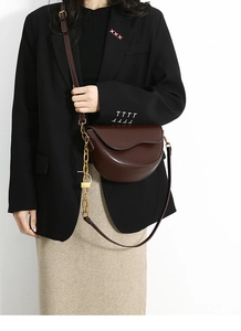 Detail of dark brown semi-circle flap bag with gold chain and lock charm decor