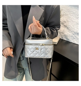 Detail of silver quilted bucket bag with golden flower clasp and chain strap
