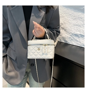 Detail of white quilted texture and gold flower logo on this elegant crossbody bag