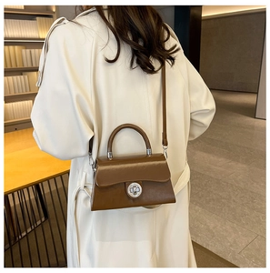 Sac bandoulière marron caramel avec fermoir métallique sur un modèle en bibliothèque